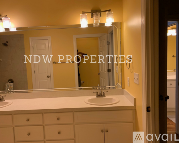 A bathroom with a sink, mirror, and lighting fixture.