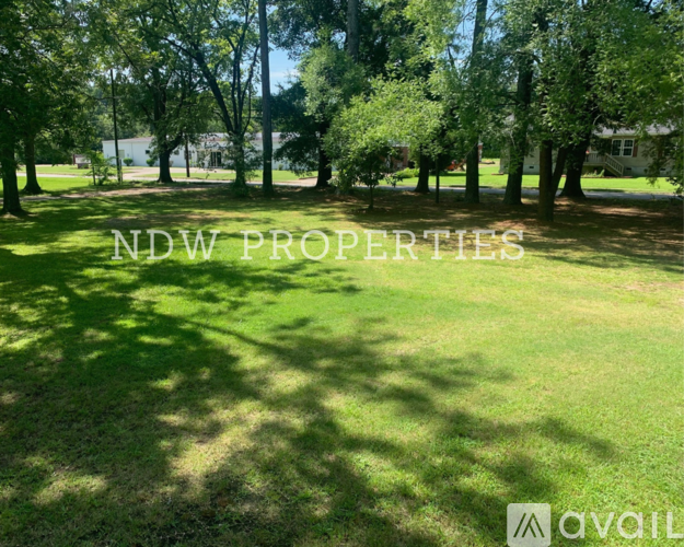 A grassy area with trees and the text "NDW PROPERTIES" overlaid on the image.