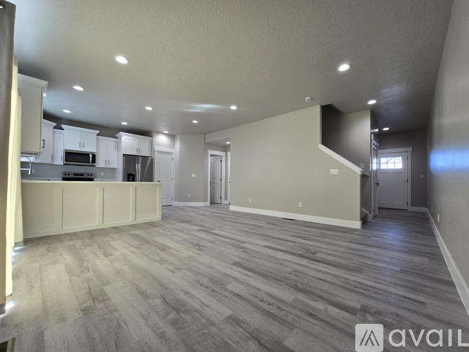 A spacious living room with a kitchen area in the background.