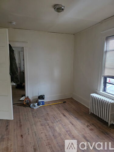 A room with wooden floors and a window with blinds.