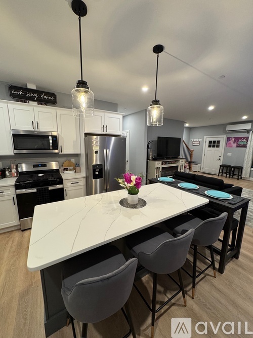 A modern kitchen with a large island and grey chairs.