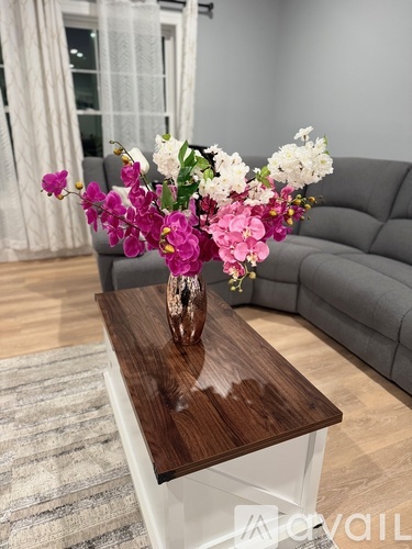 A vase of flowers sits on a wooden table in a living room.