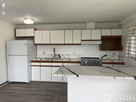 A kitchen with white cabinets and a white refrigerator.