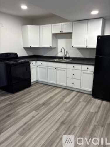 A kitchen with black appliances and white cabinets.