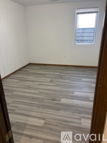 A room with wooden flooring and a window.