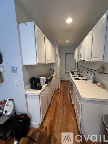 A kitchen with white cabinets and a wooden floor.