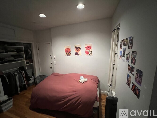 A bedroom with a red bedspread and pictures on the wall.