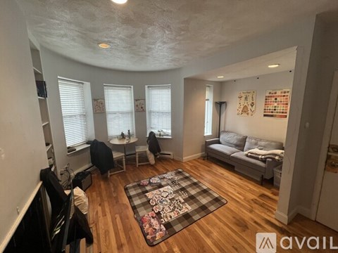 A living room with a checkered rug in the center and a couch to the right.