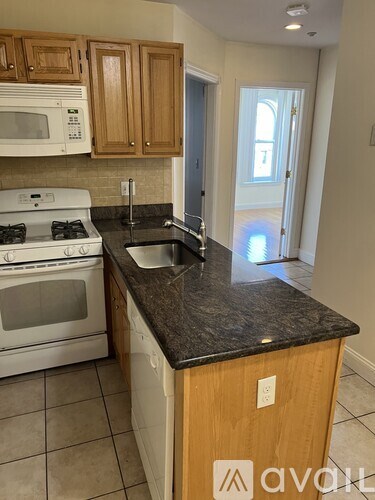 A kitchen with a white stove and a black counter top.