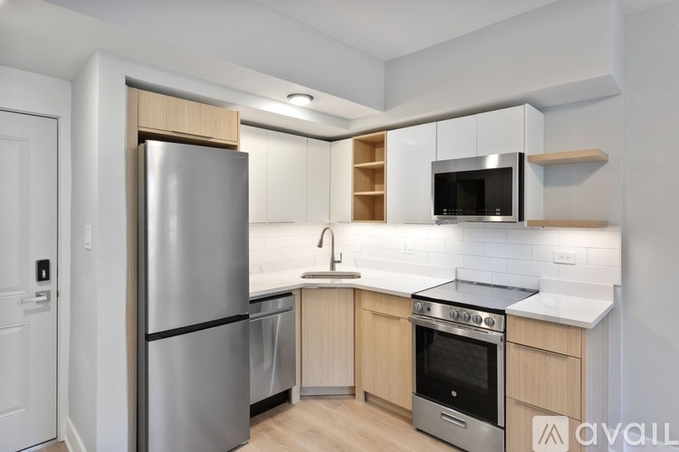A kitchen with a refrigerator, oven, microwave, and sink.