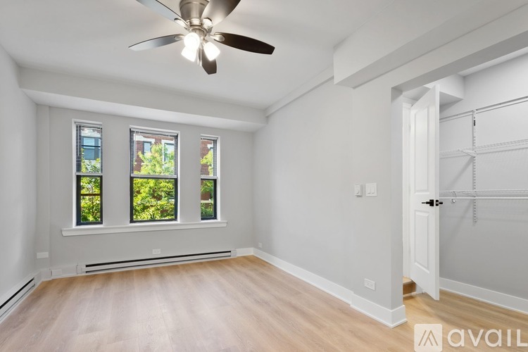 A room with a ceiling fan and a window overlooking greenery.