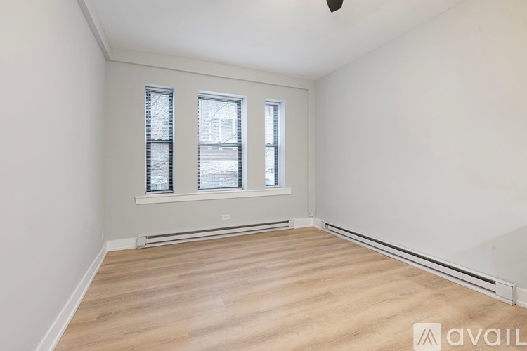 A room with wooden flooring and two windows.