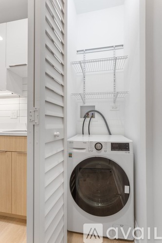 A white washing machine is in a cabinet with a white door.