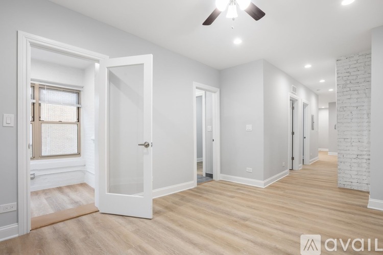 A spacious room with a ceiling fan and lighting, and a doorway leading to another room.