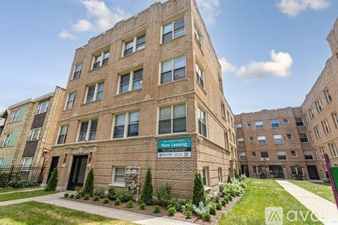 A brick building with a sign that says "Now Leasing" in front of it.