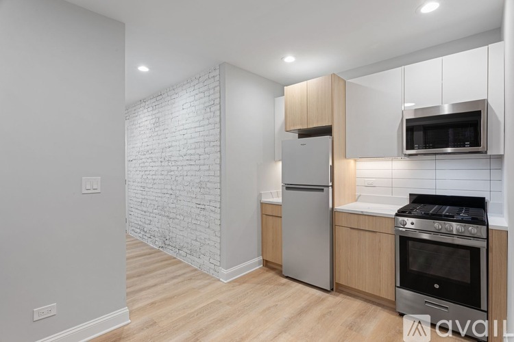 A kitchen with a white brick wall and wooden cabinets.