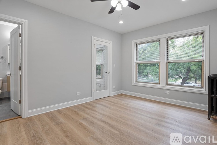 A room with a ceiling fan and a window overlooking trees.