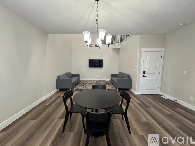 A living room with a black table and chairs, a television, and a chandelier.