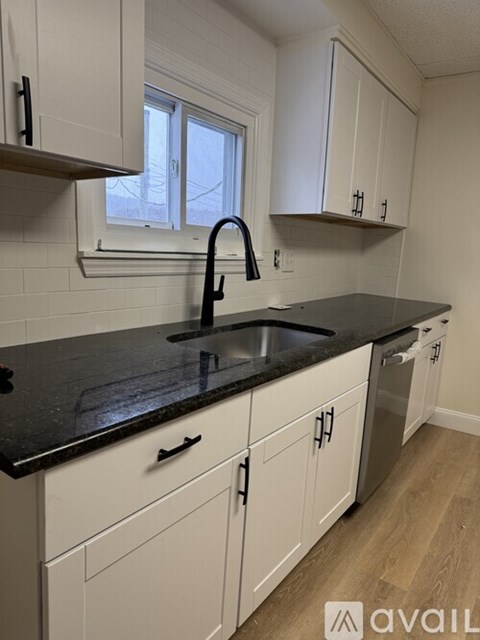 A kitchen with white cabinets and a black countertop.