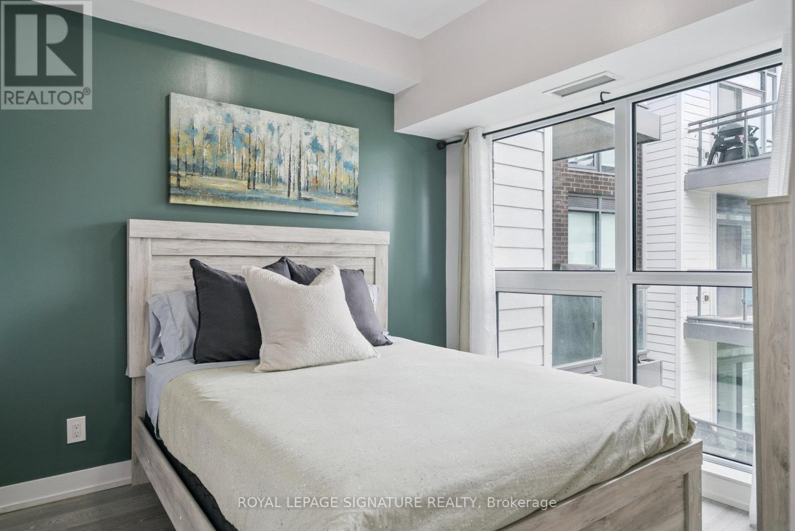 A bedroom with a large bed and a painting on the wall.