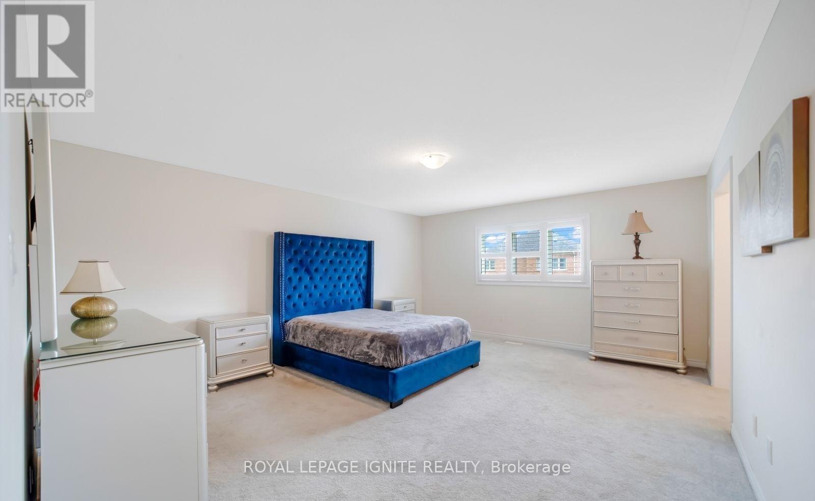 A bedroom with a blue bedspread and a white dresser.