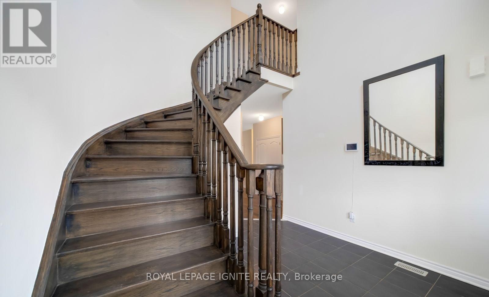 A wooden staircase with a metal railing and a mirror on the wall.