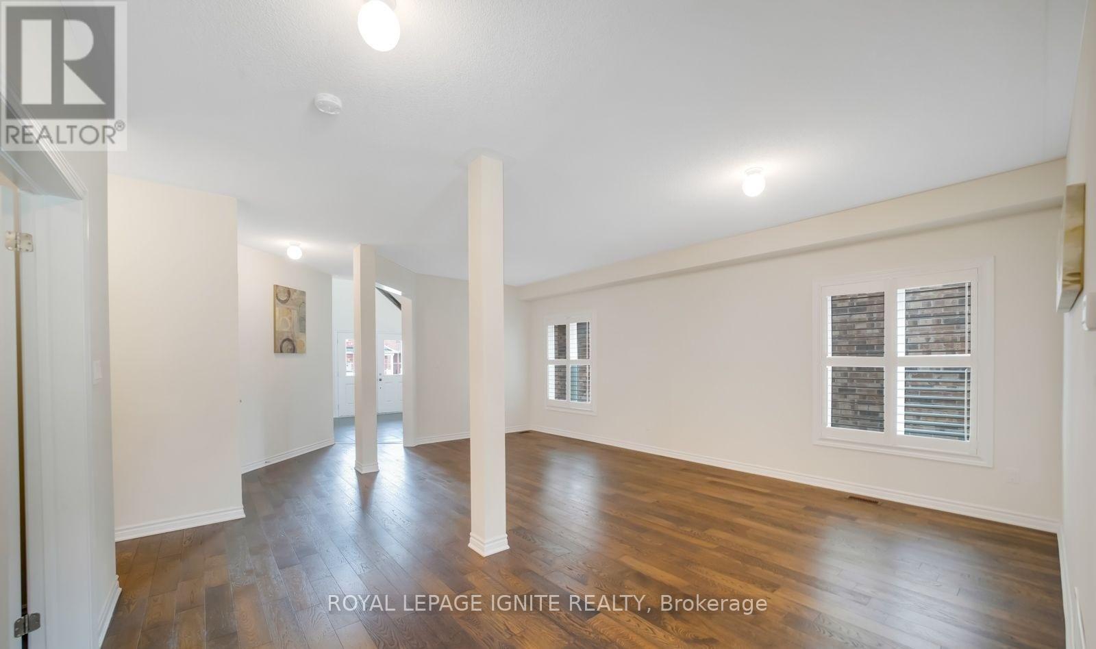 A spacious room with wooden floors and white walls, with a doorway leading to another room visible in the distance.