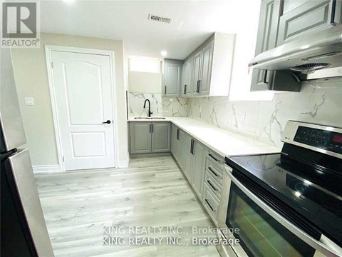 A kitchen with a black stove top oven and white cabinets.