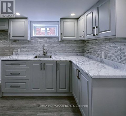 A kitchen with grey cabinets and a marble countertop.
