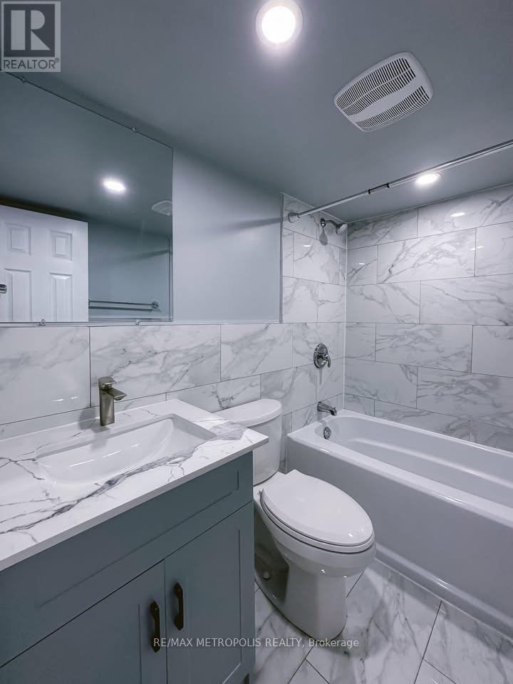 A white bathroom with a marble counter top and a white toilet.
