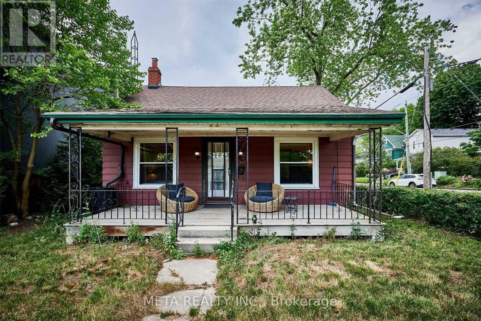 A small red house with a porch and a green lawn.