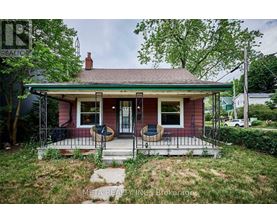 A small red house with a porch and a green lawn.