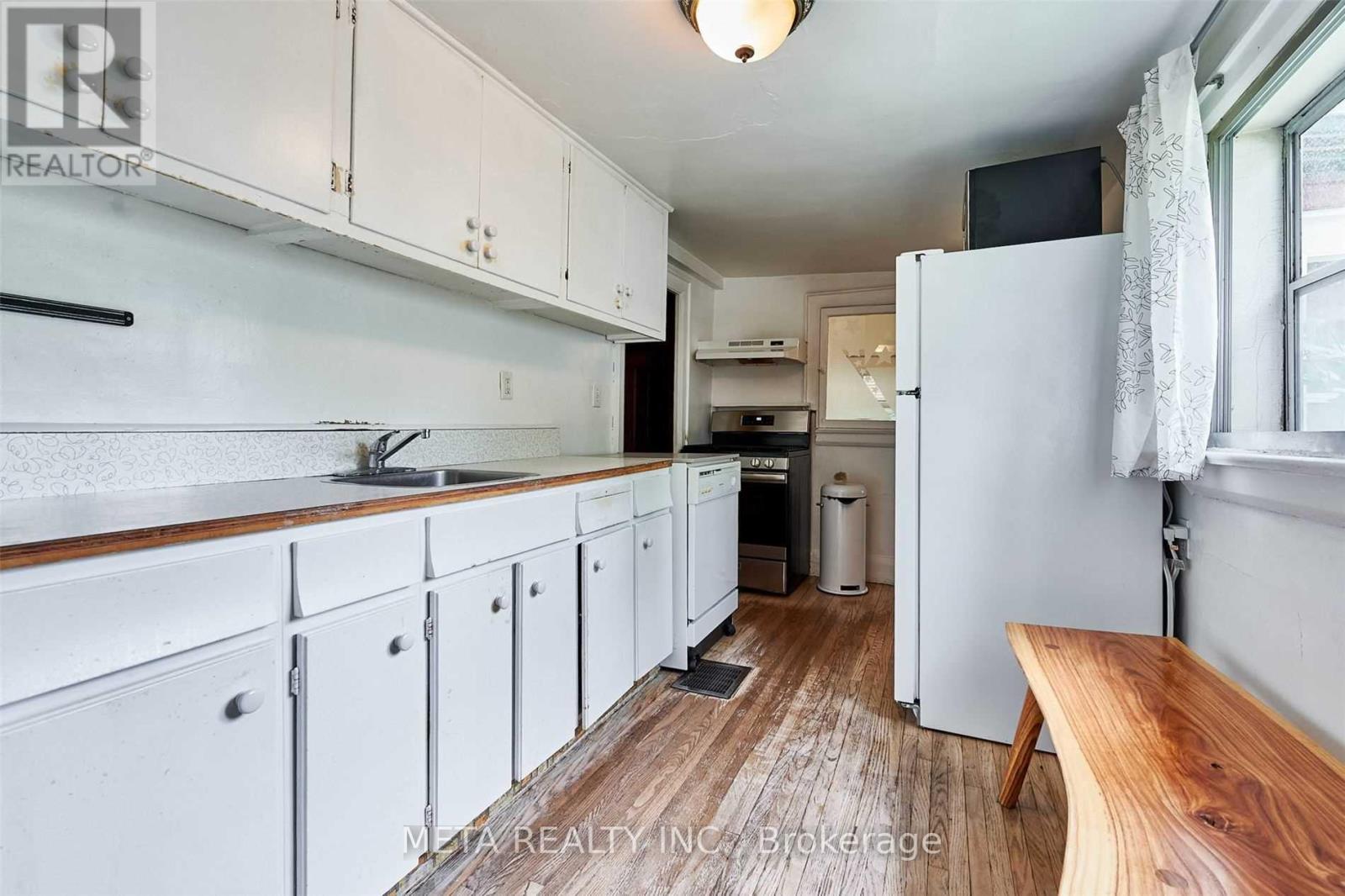 A kitchen with white cabinets and a wooden floor.