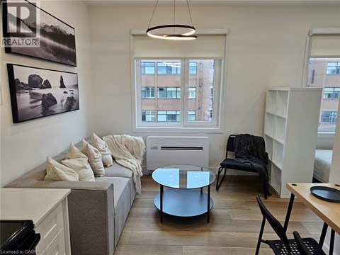 A living room with a grey couch, a black chair, and a round glass table.