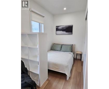 A bedroom with a bed, pillows, and a painting on the wall.