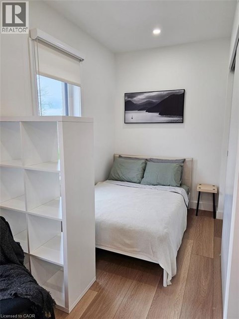 A bedroom with a bed, pillows, and a painting on the wall.