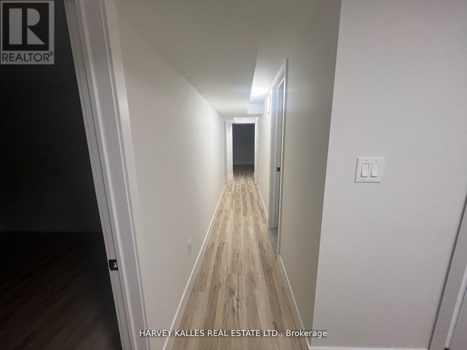 A long hallway with wood flooring and white walls.