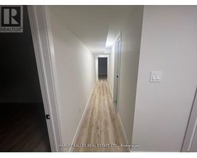 A long hallway with wood flooring and white walls.