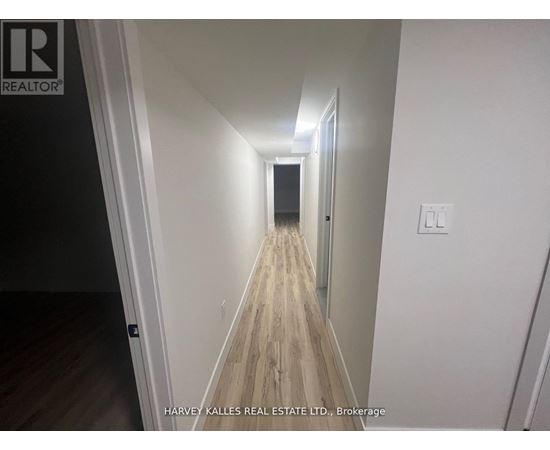 A long hallway with wood flooring and white walls.
