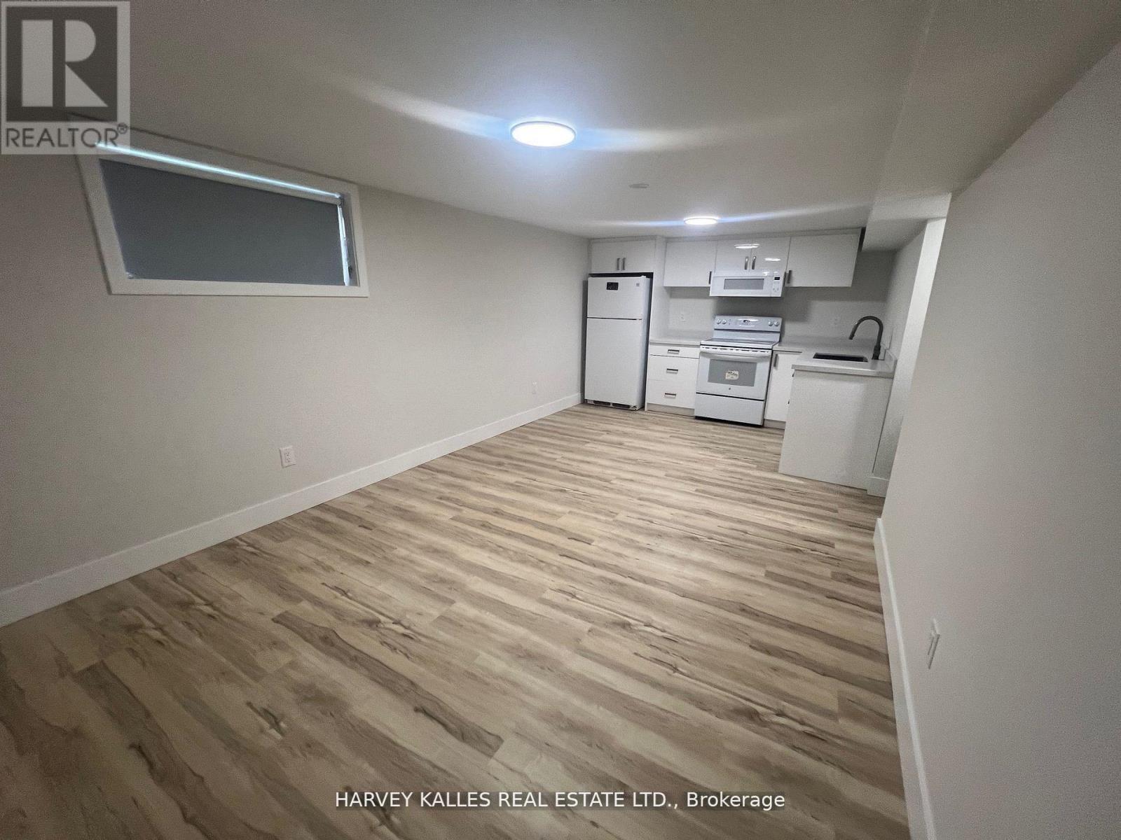 A kitchen area with wooden flooring and white appliances.