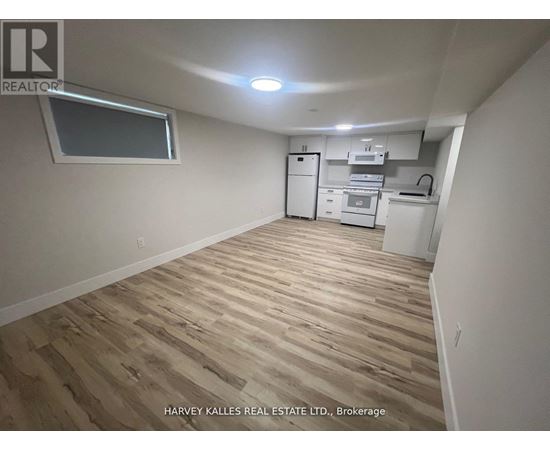 A kitchen area with wooden flooring and white appliances.