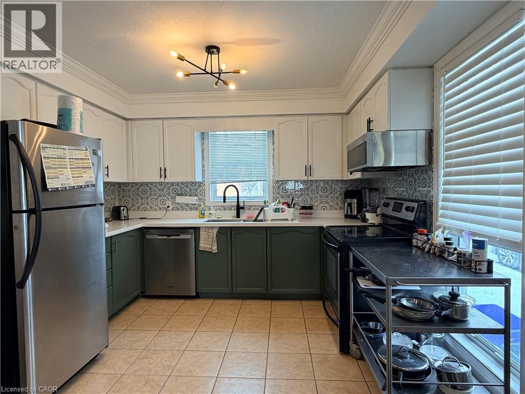 A kitchen with a refrigerator on the left and a stove top oven on the right.