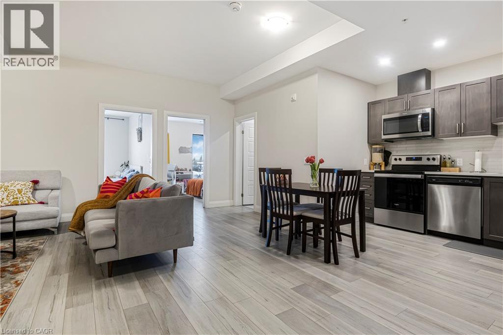 A modern kitchen with a grey couch and wooden chairs.