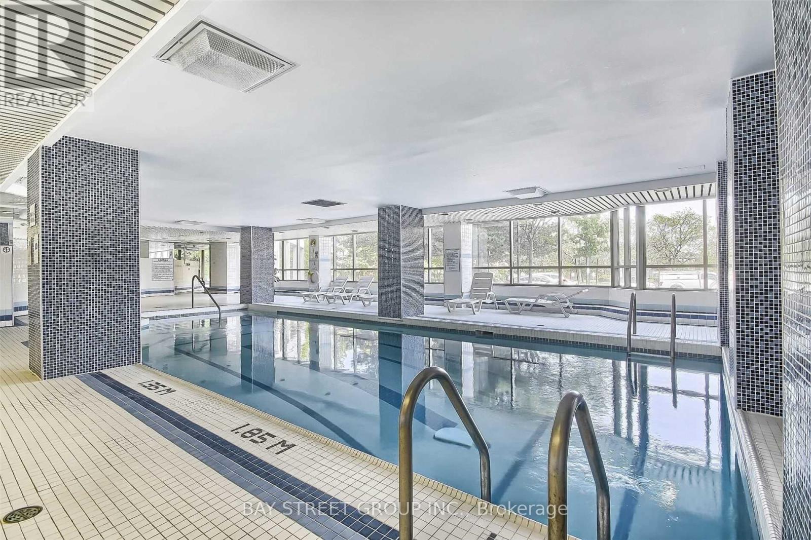 A large indoor swimming pool with a glass wall and tiled floor.