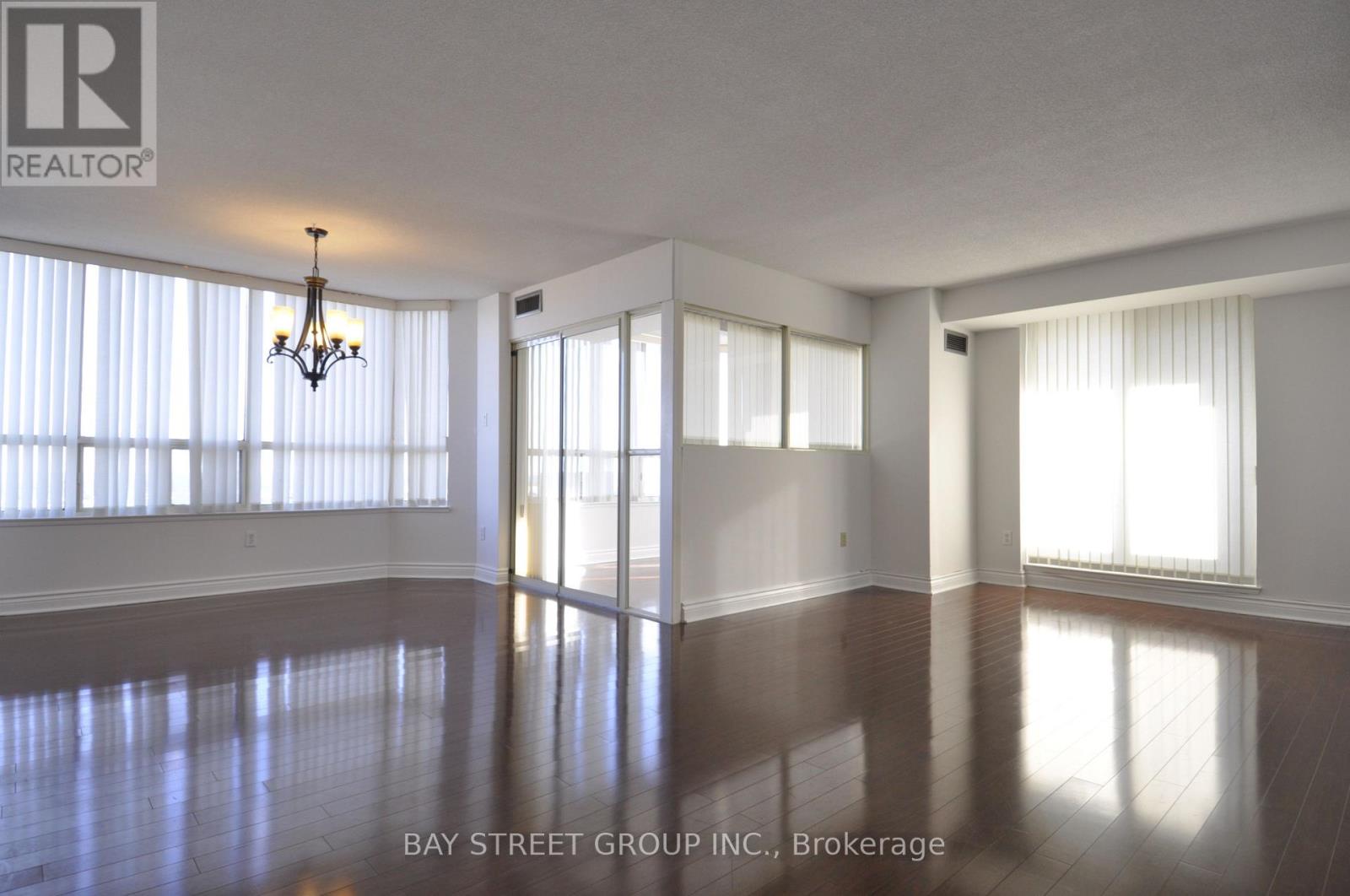 A spacious room with a chandelier and large windows.