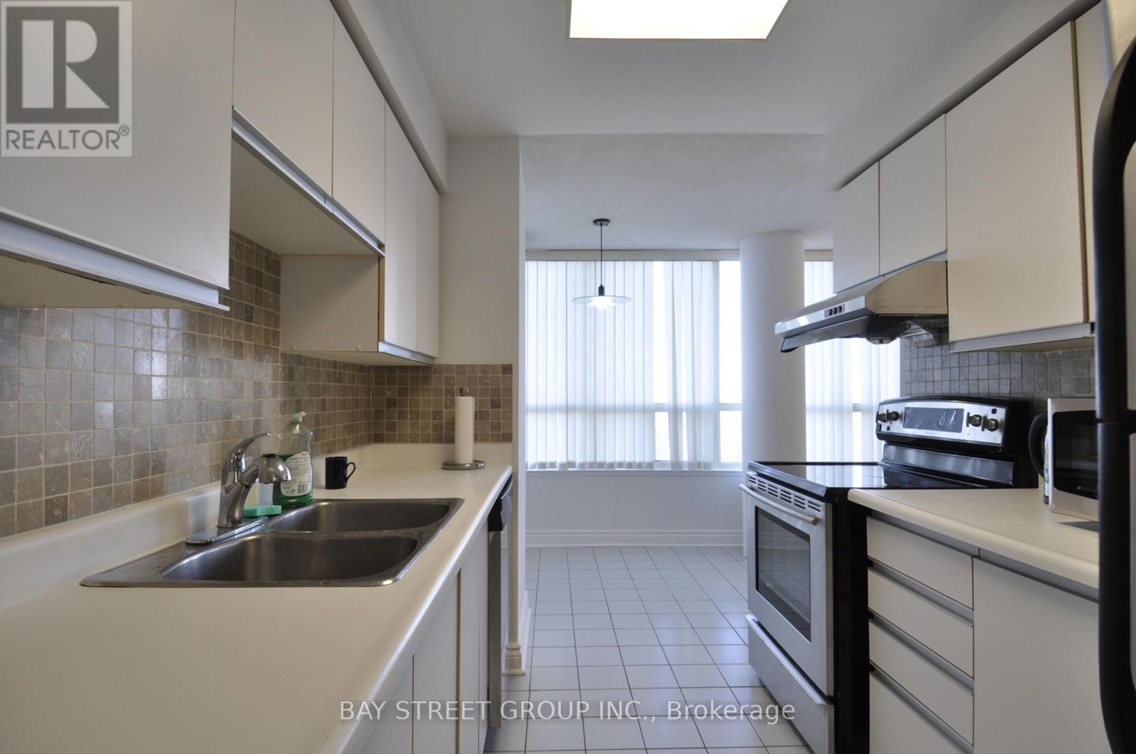 A kitchen with white cabinets and a tiled backsplash.