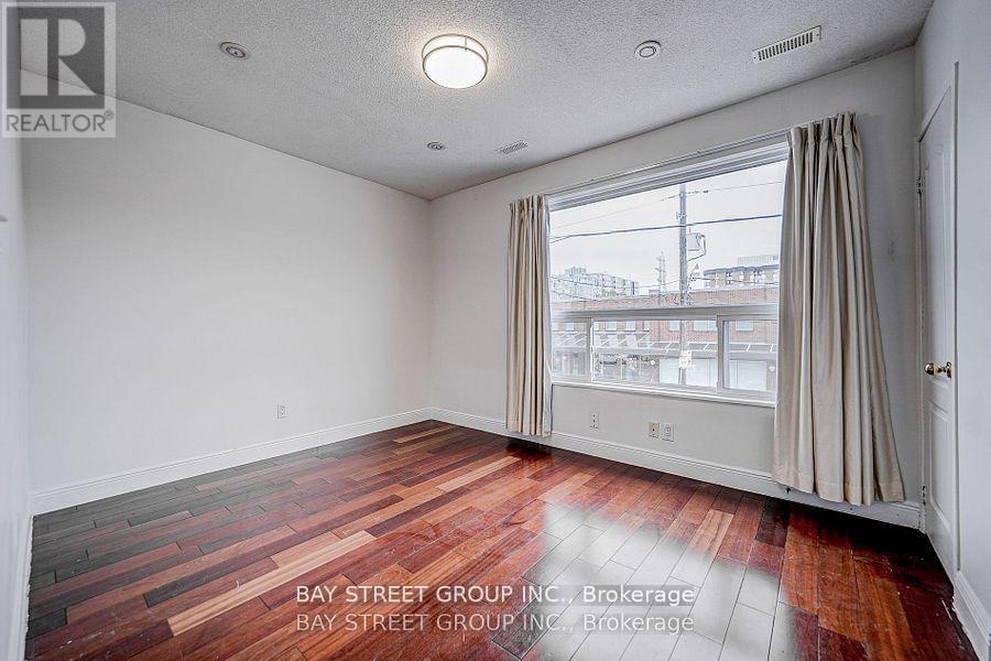 A room with a wooden floor and a window with curtains.