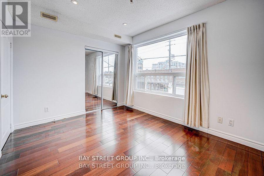 A room with a wooden floor and a sliding glass door leading to a balcony.