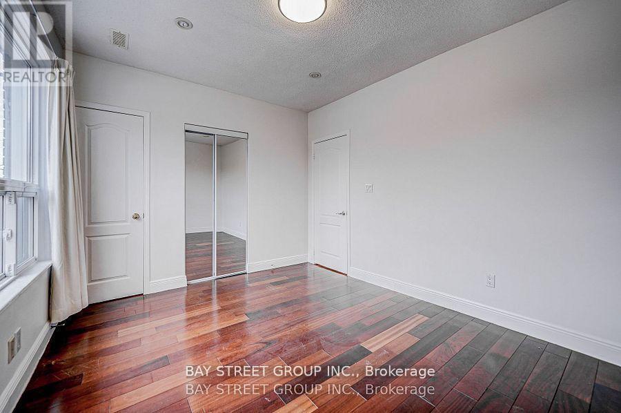 A room with wooden floors and white walls, with a window on the left side.