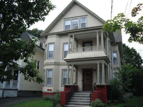 A two-story house with a red door and a balcony.